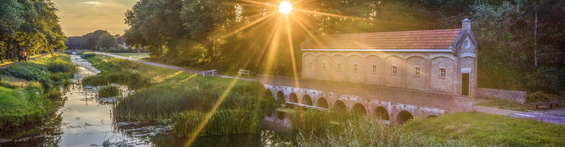 Een spectaculaire zonsondergang met gouden stralen die weerkaatsen in een vijver in het Springendal bij Nutter.